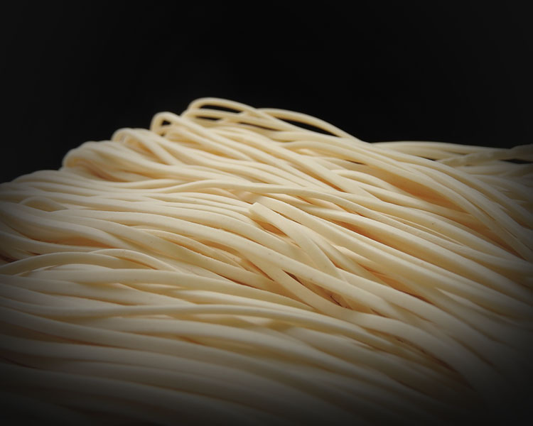 Front view of a pile of raw thin noodles  isolated on black background. Food ingredients. Asian, Taiwanese cuisine ingredients. With copy space.